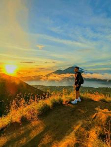 a man standing on a hill looking at the sunset at Batur Volcano Basecamp in Kubupenlokan