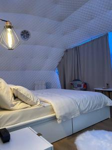 a bedroom with a large white bed with a window at WildGlampingArieseni in Arieşeni