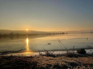 a sunset over a body of water with birds flying at Apartmán Lodenica in Piešťany