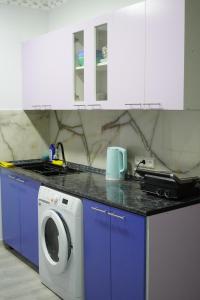 a kitchen with a washing machine and blue cabinets at Aragats Hostel & Guest House in Gyumri