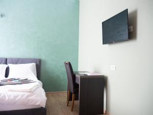1 dormitorio con 1 cama y escritorio con TV en Hotel Rezime, en Zenica