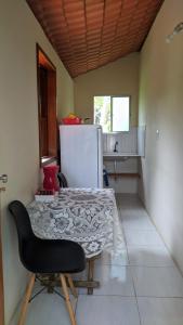 a kitchen with a table and a chair and a refrigerator at Kitnete Aconchegante in Itacaré