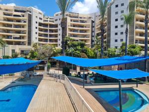 een zwembad met blauwe parasols voor gebouwen bij Amazing Apartment in Raanana & Swimming up to 4 guests pool and Jacuzzi in Ra‘ananna