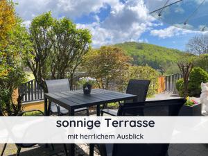 バート・ザクサにあるDer Fuchsbau - Fewo LePetit - im sonnigen Harz - Hunde willkommen - 100m bis zum Wald - FREE WLANの山のあるパティオ(黒いテーブルと椅子付)