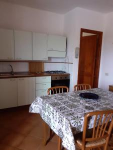 a kitchen with a table with chairs and a tablecloth at casa rosa nel residence mirice con piscina ,wifi,climatizzatore - vicino al mare in Aglientu