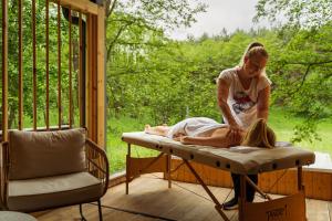 a woman laying on a bed on a porch at Bakony Deep Forest Vendégház in Bakonyszentlászló