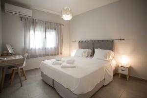 a bedroom with a large white bed and a desk at Serenity Suites Corfu in Potamós