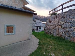 a stone wall next to a building with a window at Rifugio Cuneck in Velo Veronese
