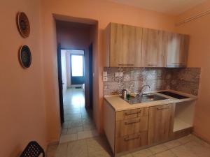 cocina con armarios de madera, lavabo y pasillo en Niki's house, en Agia Triada