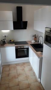 a kitchen with white cabinets and a black appliance at Appartement centre-ville avec terrasse in Montpellier