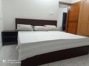 1 dormitorio con 1 cama grande con sábanas y almohadas blancas en FAB HOUSE, en Thekkady