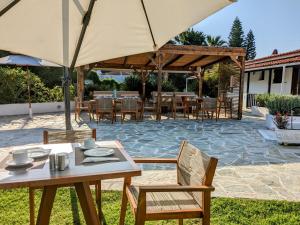 a patio with tables and chairs and an umbrella at Villa Karina in Kolios