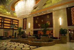 a lobby of a hotel with plants and a large chandelier at Foshan Royal Prince Hotel in Shunde