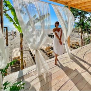 a woman in a white dress walking under a veil at Aqua Palm Resort in Sukhum