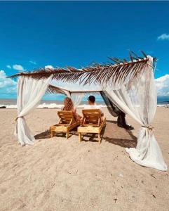 two people sitting in chairs under a canopy on the beach at Aqua Palm Resort in Sukhum