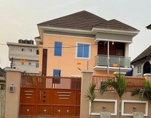 a house with a orange fence and a gate at Lovadek Spacious Apartment in Lagos
