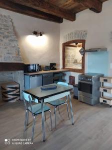 uma cozinha com mesa e cadeiras num quarto em CHEZ GUETOU Gîte de charme en Lozère em La Tieule