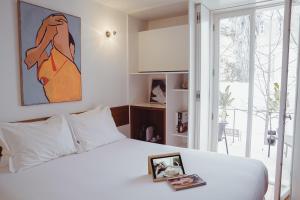 a bedroom with a white bed with a painting on the wall at The Late Birds Lisbon - Gay Urban Resort in Lisbon
