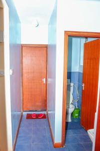 a bathroom with a shower with a toilet and a door at Tiamcy homes in Kisumu