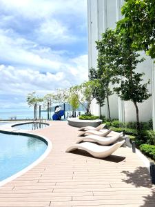 a row of lounge chairs next to a swimming pool at The Shore CBD Kota Kinabalu By LAXZONE SUITE in Kota Kinabalu