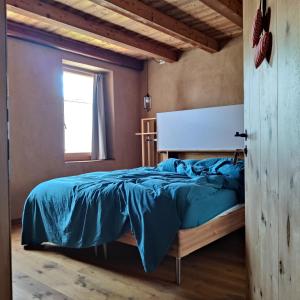 una camera da letto con un letto con un piumone blu e una finestra di Casa Zefìra a Pren