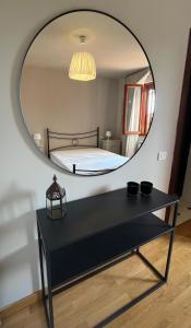 uno specchio sopra un tavolo nero con un letto in una stanza di Le case di Anita in Toscana - Arezzo ad Arezzo