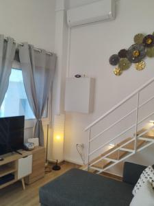 a living room with a staircase and a television at Spata center loft in Spata