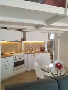 a kitchen with white cabinets and a glass table at Spata center loft in Spata +16 photos