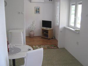 ein weißes Esszimmer mit einem Tisch und einem TV in der Unterkunft Matea in Crikvenica