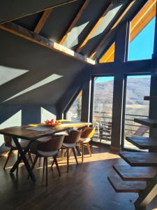 a dining room with a table and chairs and windows at Kira Apartments Mavrovo in Mavrovo +23 photos