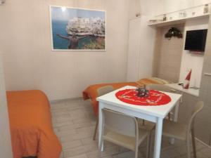 ポリニャーノ・ア・マーレにあるGIUAMAR casa vacanzaの白いテーブル、テーブル、椅子が備わる小さな客室です。