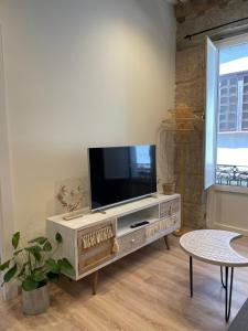 a living room with a flat screen tv on a wooden entertainment center at A Das Marias VINTAGE in Ourense