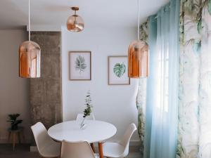 une salle à manger avec une table et des chaises blanches dans l'établissement Mikasika - Duplex Apartment with seasonal swimming pool & walking distance from the beach, à Cala del Moral