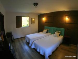 a bedroom with two beds with white sheets and a window at Rilhadas Casas de Campo in Fafe