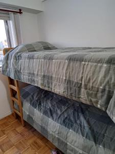 Una cama con un edredón gris encima. en Lo de Susi en Buenos Aires