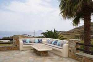 a couch sitting on a patio next to a palm tree at SerenSea Bliss, Naousa, Kythnos in Kithnos