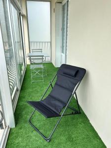 L'Entre Deux Rêves في Beaumont-lès-Valence: كرسي على شرفة مع عشب أخضر