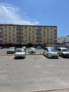 un estacionamiento con autos estacionados frente a un edificio en Апартаменты у Натальи, en Aktau