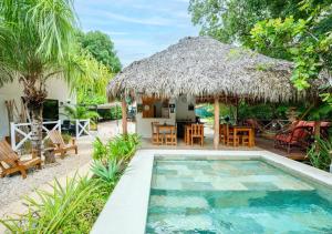 a villa with a swimming pool and a thatch roof at Antema Lodge Secteur Tamarindo, piscine, yoga, gym, jungle et paix in Tamarindo