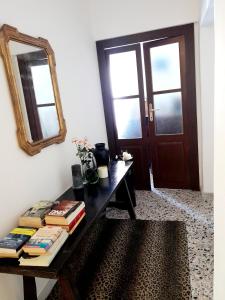 Habitación con mesa con libros y espejo. en Da Julia en Oristano