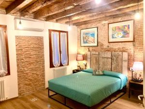 a bedroom with a green bed and a brick wall at Old town Chioggia apartments in Chioggia