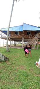 dos personas de pie en el césped cerca de un edificio en hospedaje en las islas de San blas habitacion privado con baño compartido en Achoertupo
