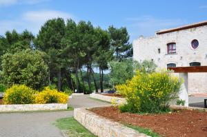 un edificio con alberi e fiori in un parco di Apulia Victor Country Hotel ad Alberobello