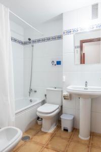 Baño blanco con aseo y lavamanos en La Ensenada, apartamento junto al mar, en Barbate