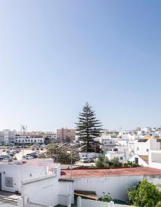 vistas a una ciudad con edificios blancos y un árbol en La Ensenada, apartamento junto al mar, en Barbate