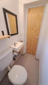 La salle de bains est pourvue de toilettes blanches et d'un lavabo. dans l'établissement Monoambiente pequeño, à Carmen de Patagones
