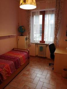 1 dormitorio con cama, escritorio y ventana en Appartamento Il Cedro en Rosia