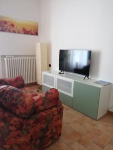 sala de estar con TV, sofá y silla en Appartamento Il Cedro en Rosia