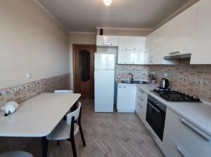 Il comprend une cuisine équipée d'un réfrigérateur blanc et d'une table. dans l'établissement 2-х кімн квартира в новобудові, à Ternopil