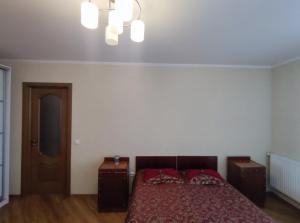 - une chambre dotée d'un lit avec des draps rouges et un lustre dans l'établissement 2-х кімн квартира в новобудові, à Ternopil